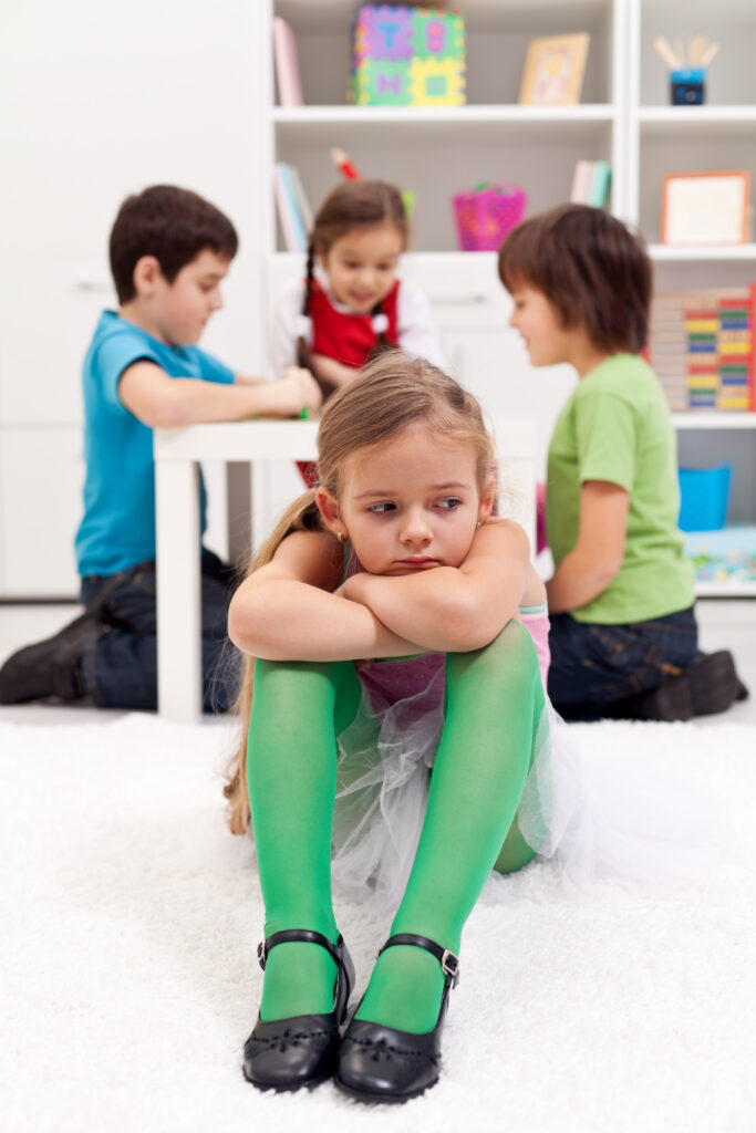 USP: Teen & Child Social Skills - young girl sitting away from a group looking disappointed
